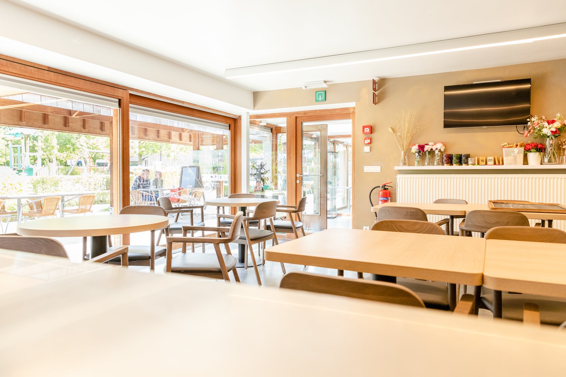 Binnenruimte cafetaria van de Borgwalhoeve. Tafels en stoelen met zicht op overdekt terras.